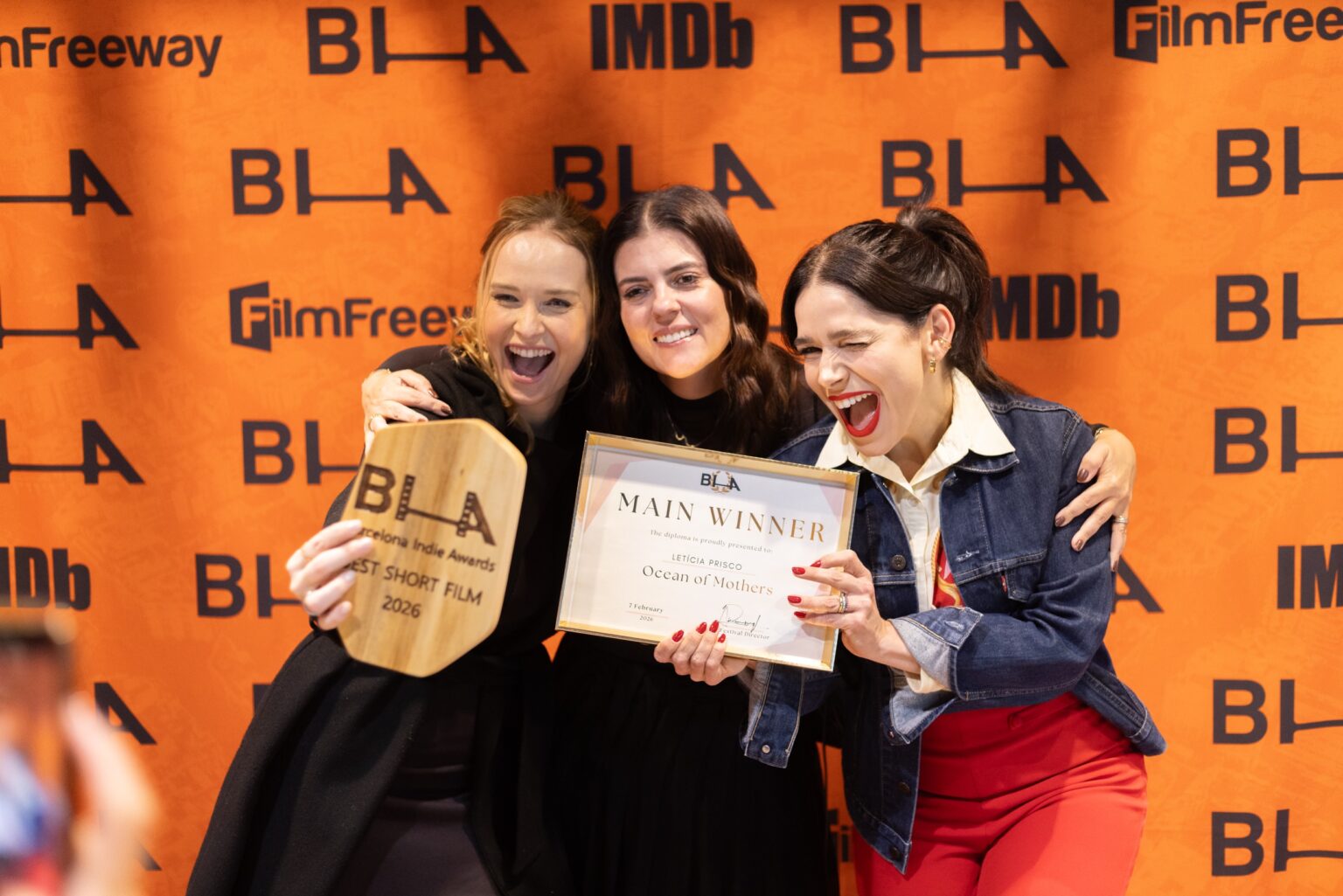 Three filmmakers celebrate at the press wall holding the Main Winner diploma for Ocean of Mothers and the Best Short Film 2026 award