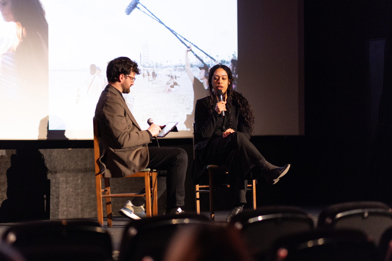 On-stage Q&A at the Barcelona Indie Awards 2026: a filmmaker answers questions, microphone in hand, in front of a projected film still