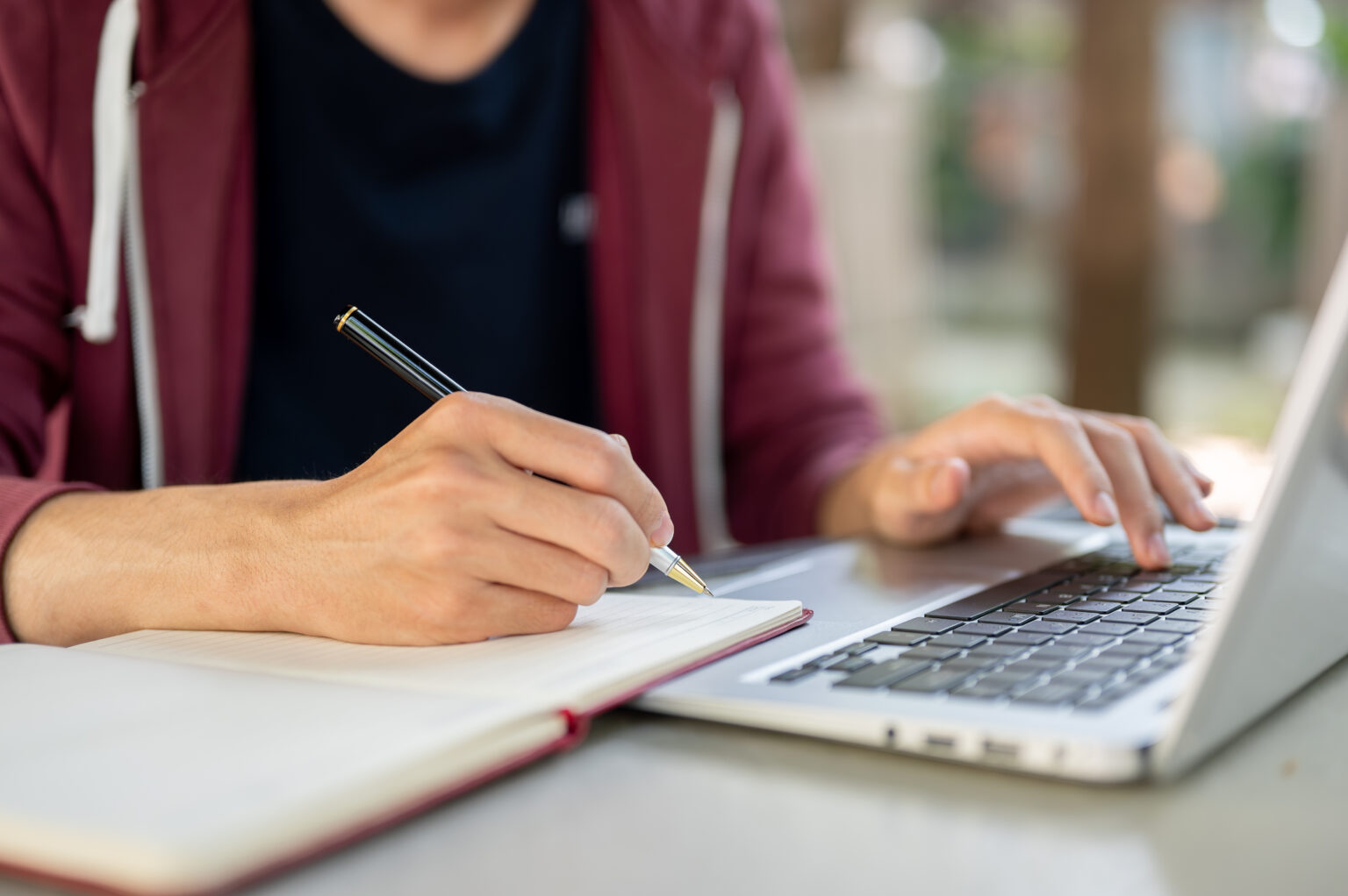 A hand writing notes in a notebook with a pen