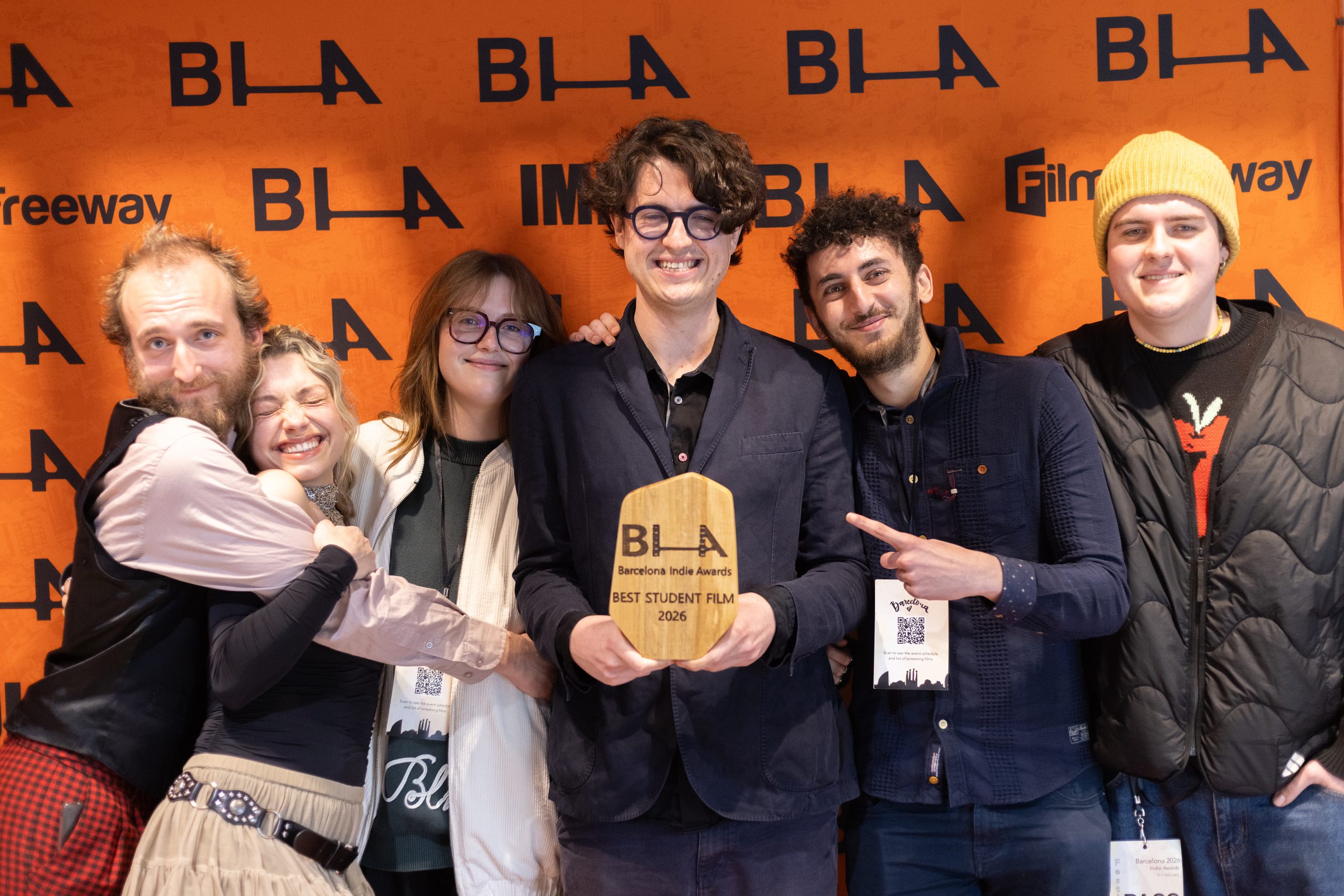 A film team celebrating with their Best Student Film 2026 trophy at the press wall