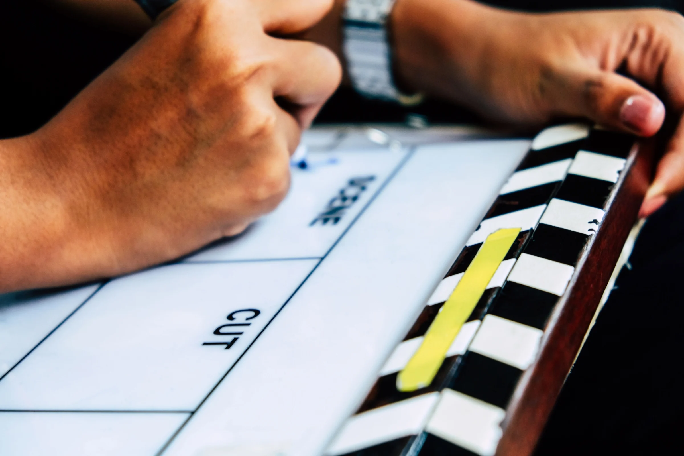 A crew member marking a clapperboard labeled Cut, with a strip of yellow tape across the clap sticks